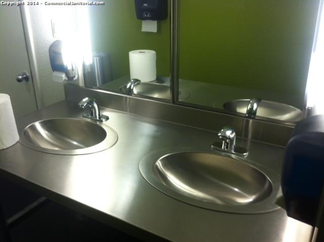 2 stainless steel sinks that are cleaned by a day porter in an office